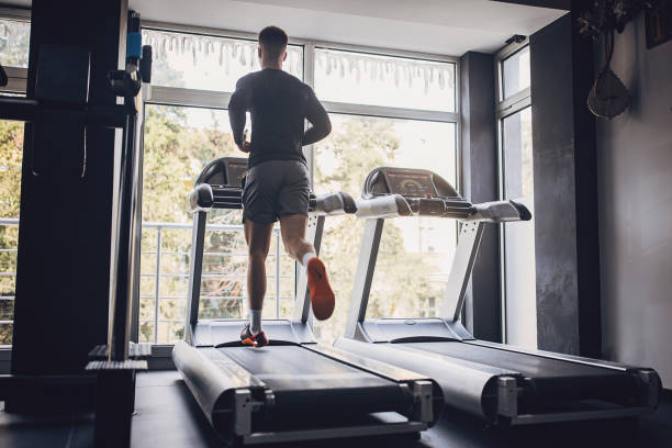 istock Man running on treadmill near large gym windows. 2172935329