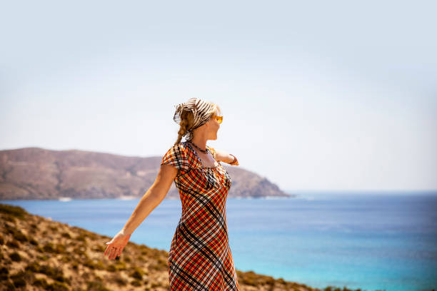 Woman  standing on a cliff above blue sea and enjoy fresh air and view