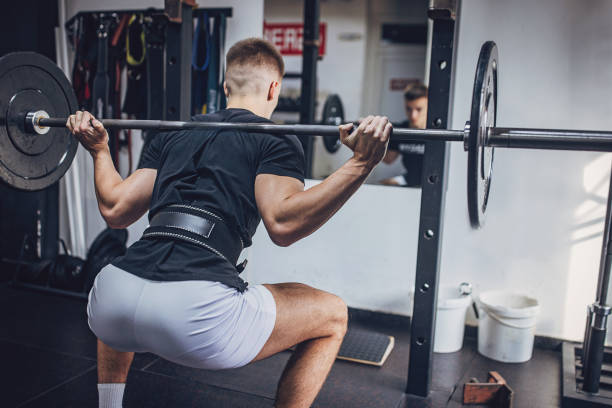 istock Man doing a squat with a barbell in a gym 2172940345