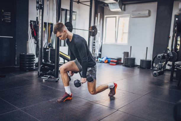 istock Man performing lunge exercise with dumbbells at the gym 2172942585
