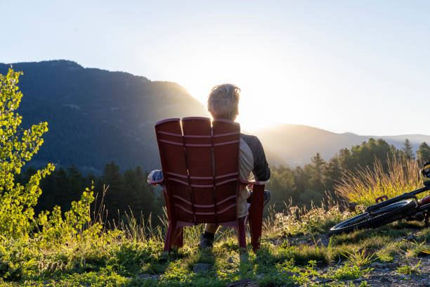 Mature man relaxes in mountain meadow at sunrise