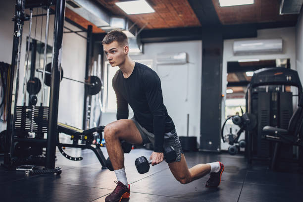 istock Athletic man lunge exercise with weights in gym 2172944041