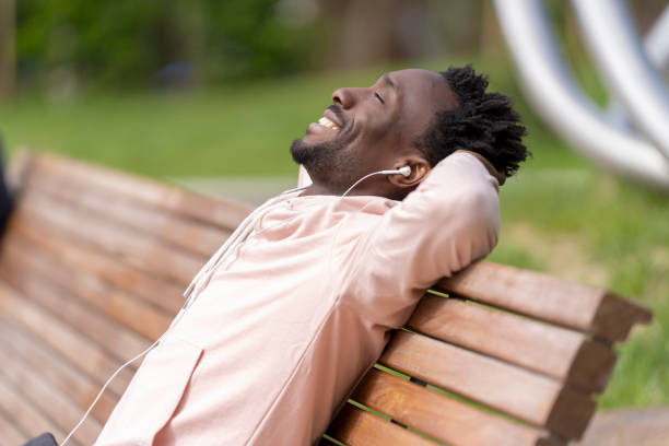 istock The man smiles while reclining on a park bench, enjoying music through his earbuds. 2172944426