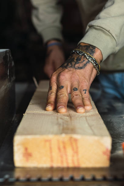 Unrecognizable crop male woodworker without a thumb processing piece of wood at workbench while working in joinery