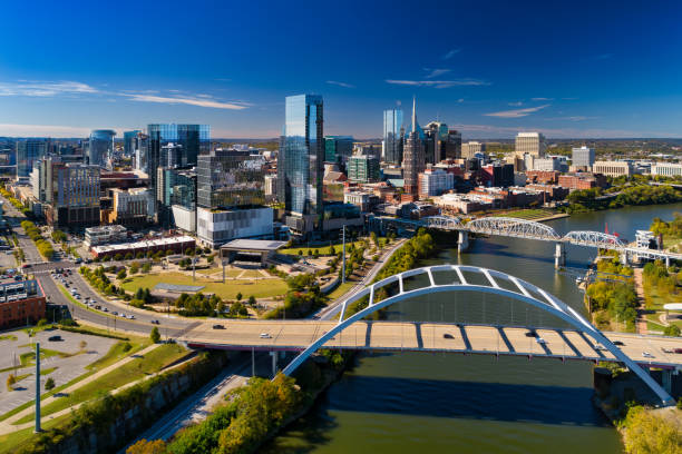 Nashville Skyline And Bridges Aerial An aerial skyline view of Nashville with both the Korean War Veterans Memorial Bridge (lower) and the John Seigenthaler Pedestrian Bridge (upper) over the Cumberland River, with the modern Downtown Nashville skyline. nashville tennessee bridge stock pictures, royalty-free photos & images