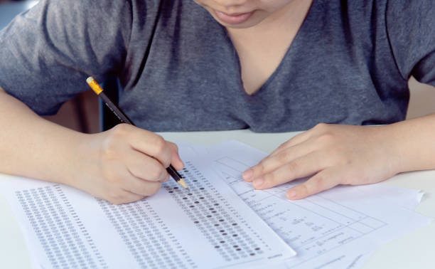 istock Students hand holding pencil writing selected choice on answer sheets and Mathematics question sheets. students testing doing examination. school exam 2172969018