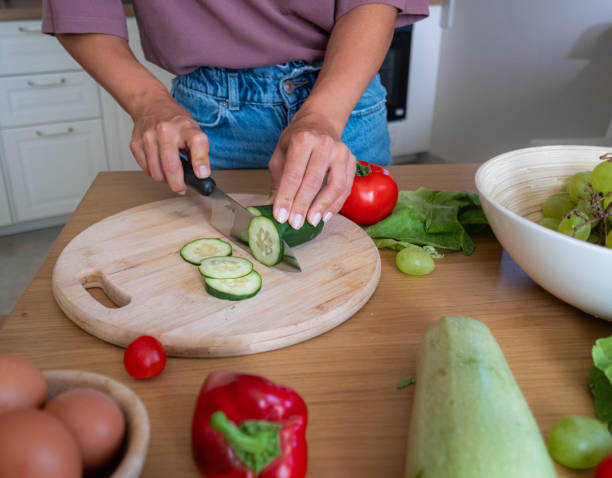 istock the woman is cutting a cucumber 2172981294