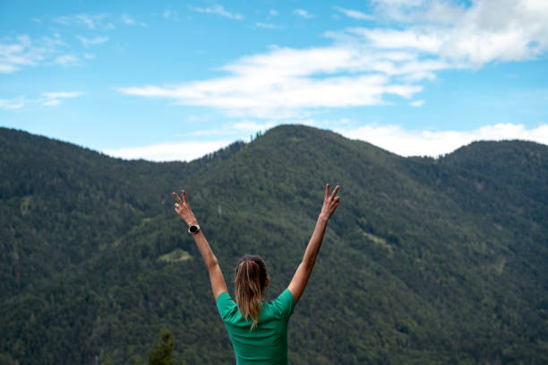 istock Woman with raised arms standing under blue sky with mountain view 2173000784