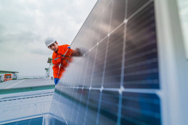 engineer man inspects construction of solar cell panel or photovoltaic cell by electronic device. Industrial Renewable energy of green power. factory worker working on tower roof.