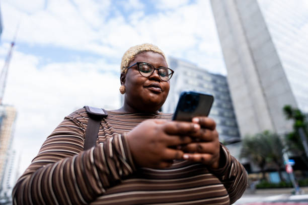 istock Young woman using mobile phone and walking through the city 2173003870