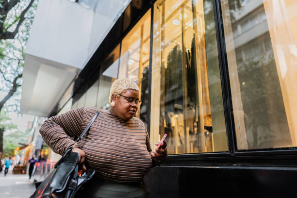 istock Young woman using mobile phone and walking through the city 2173004536