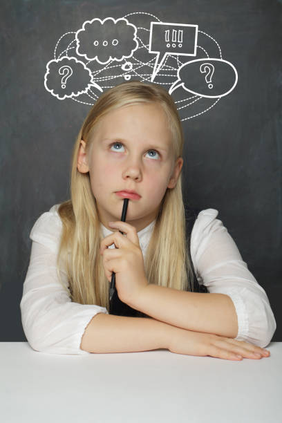 istock Thinking child girl and thought cloud bubble with question mark above head looking up on school blackboard background 2173010322