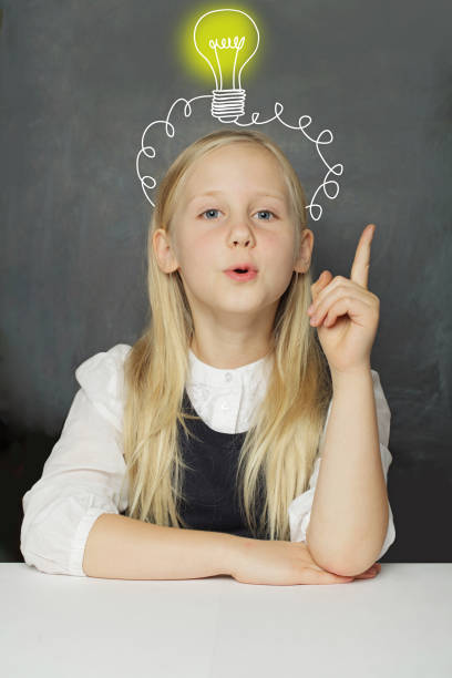 istock Curious child girl student with yellow light bulb on school blackboard background. Creativity, education and idea concept 2173010325
