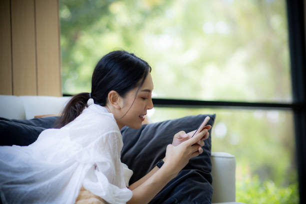 istock Cheerful woman  talking over smartphone while lying on sofa at the cozy home 2173013063