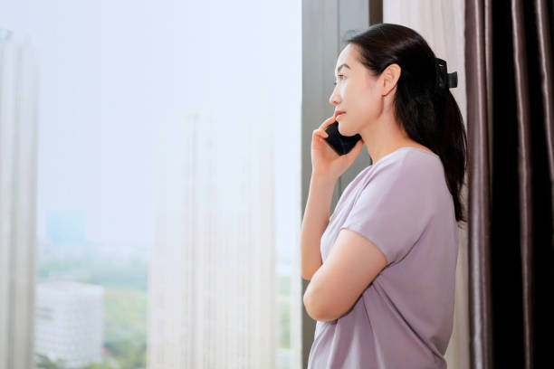 istock Woman Engaged in a Thoughtful Phone Conversation by the Window 2173027786