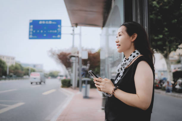 istock Woman Waiting at a City Bus Stop While Using Her Phone 2173030868