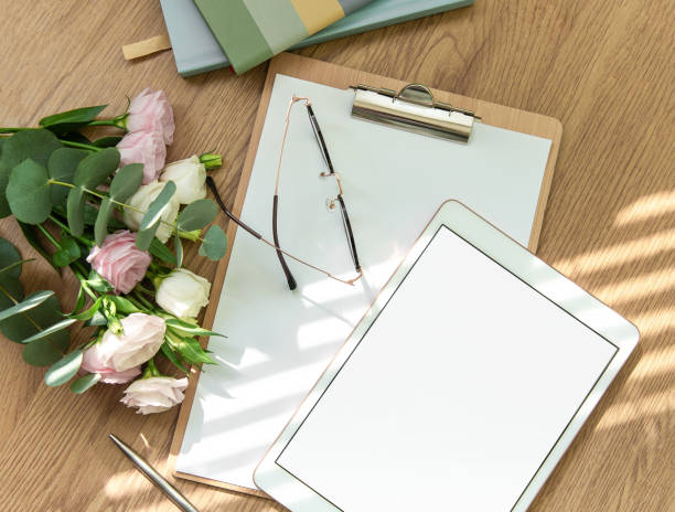 istock Stationery workspace with a blank tablet, notebook, and flowers on a wooden table, perfect for creative planning in natural light 2173045354