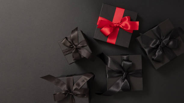 istock Black Friday Sale. Black gift boxes with ribbon bow isolated on black, top view 2173046676