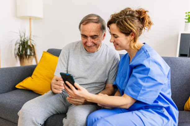 Friendly caregiver teaching her patient how to use a mobile phone