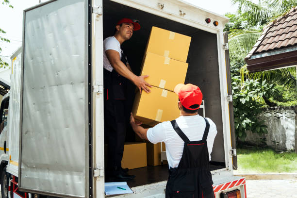 istock Asian and Caucasian workers in uniform unloading cardboard boxes from the truck. Delivery men unloading boxes and check the checklist with their coworkers. Professional delivery and moving service. 2173050735