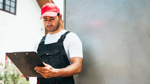 istock Asian truck driver wearing red cap holding a clipboard, checking the delivery packages checklists or paperwork and standing with a truck. Shipping cargo service, freight truck and transport logistics. 2173050737