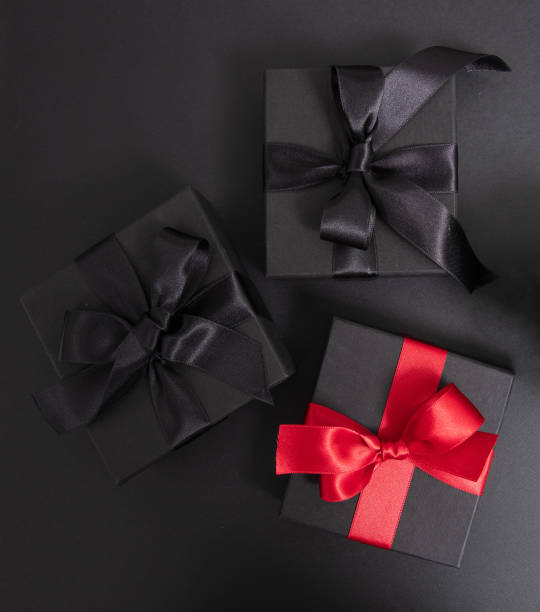 istock Black Friday Sale. Black gift boxes with ribbon bow isolated on black, top view 2173051248