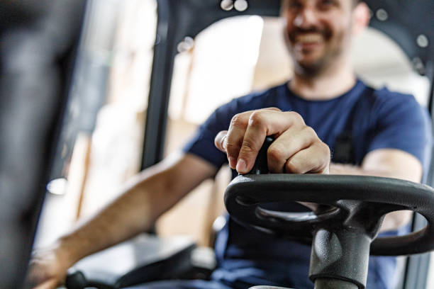Close up of unrecognizable worker managing with steering wheel while driving a forklift in a storage room.