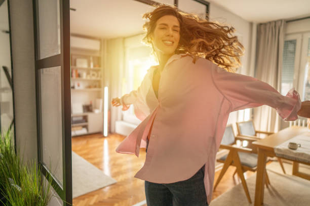 Happy young woman spinning and dancing at home on sunny day