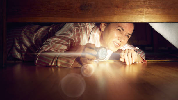 istock Emotional senior man looking under bed with flashlight, trying to find out something, Hidden secrets. 2173057404