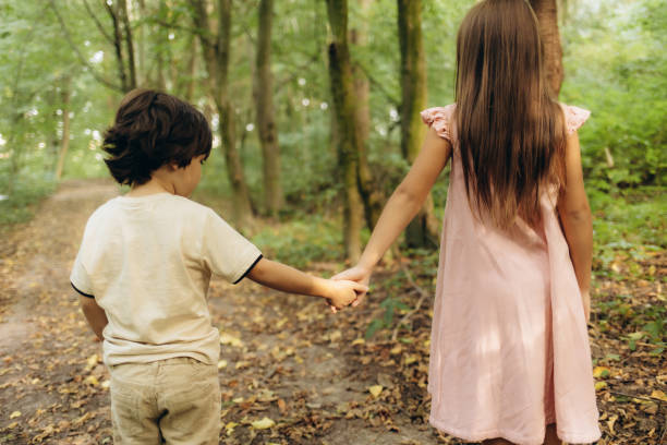 Little brother and sister walking in the forest