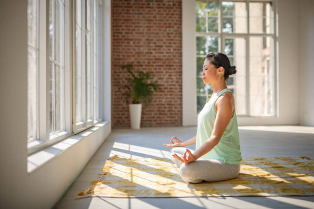 istock Person in lotus position meditating by large windows 2173063656