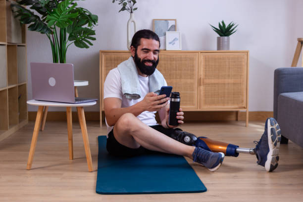 istock Smiling young man with prosthetic leg using smartphone after home workout 2173064157