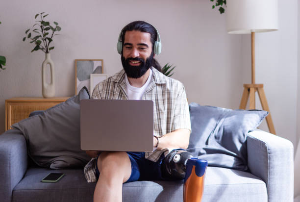 istock Young happy man with prosthetic leg using laptop at home on sofa 2173064467