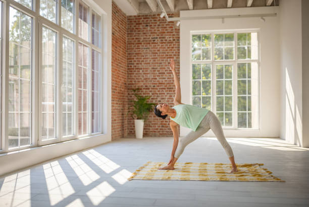 istock Woman doing triangle pose near large bright windows. 2173064539