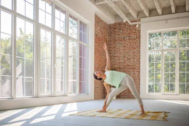 istock Woman performing triangle pose in sunny yoga studio. 2173065334