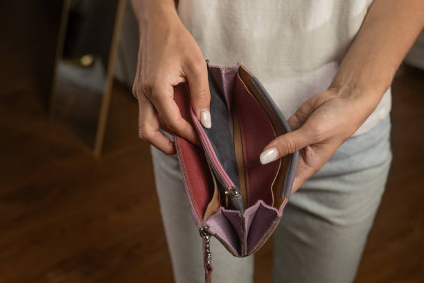 Woman revealing an empty blue wallet, showcasing financial struggles stock photo