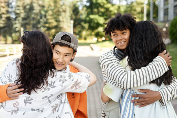 istock Teenage Boys Hugging Girlfriends while Couples Greet on Walk in Park 2173069077