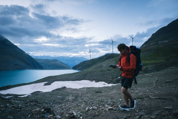istock Backpacker uses digital tablet above lake and mountains, hiking 2173071792