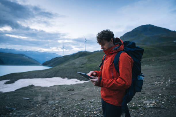 istock Backpacker uses digital tablet above lake and mountains, hiking 2173071799