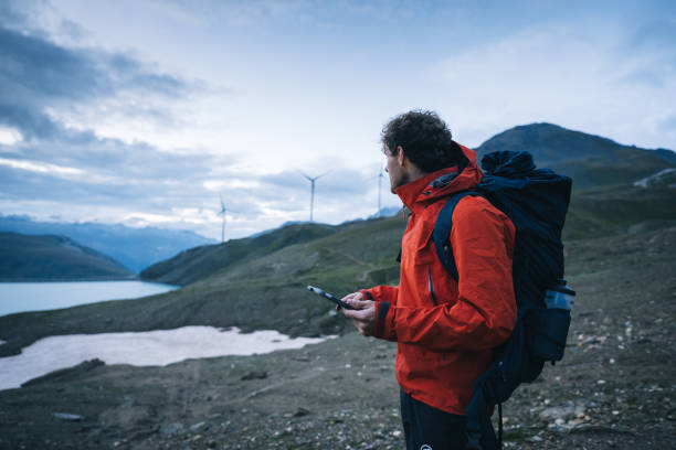 istock Backpacker uses digital tablet above lake and mountains, hiking 2173071843