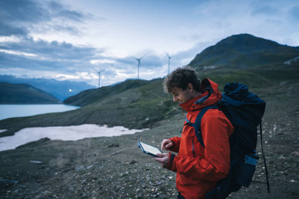 istock Backpacker uses digital tablet above lake and mountains, hiking 2173071849