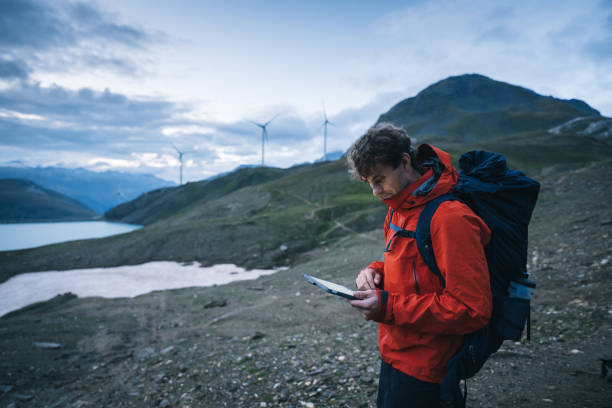 istock Backpacker uses digital tablet above lake and mountains, hiking 2173071932