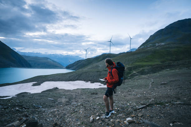 istock Backpacker uses digital tablet above lake and mountains, hiking 2173071942