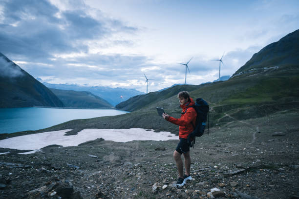 istock Backpacker uses digital tablet above lake and mountains, hiking 2173071979