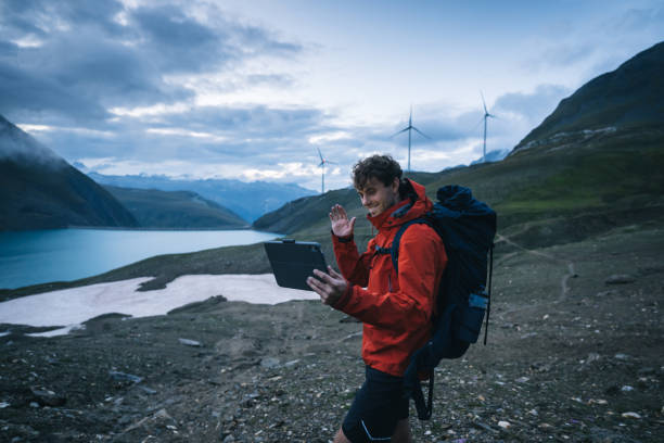istock Backpacker uses digital tablet above lake and mountains, hiking 2173072011