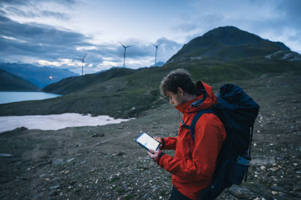 istock Backpacker uses digital tablet above lake and mountains, hiking 2173072087