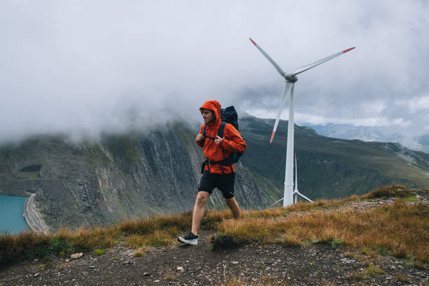 Backpacker hikes above wind turbines and lake