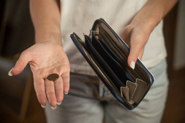istock Woman opening empty wallet showing one coin 2173073620