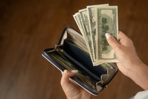 istock Counting us dollar bills by a woman while managing cash from a blue wallet 2173076128
