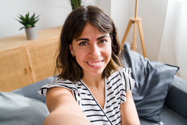 istock Beautiful woman relaxing on comfortable sofa taking selfie at home 2173076477